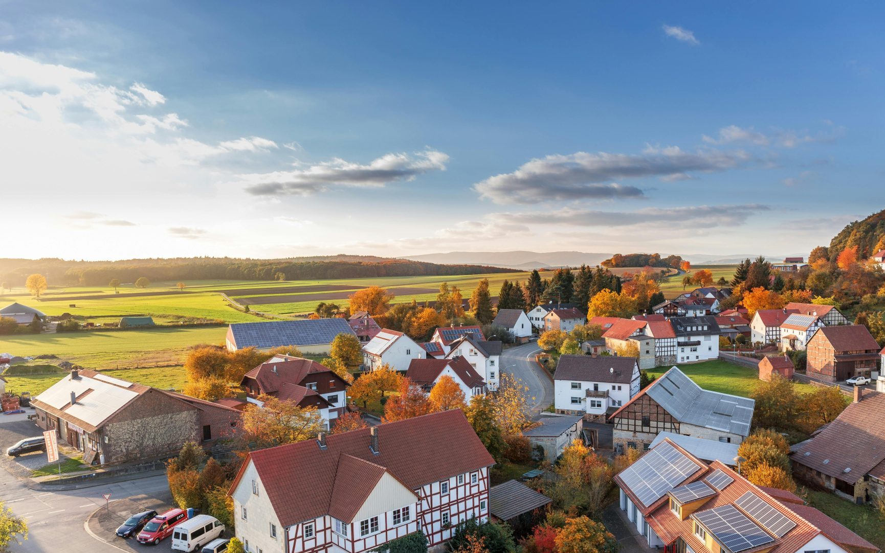 Bezaubernde Luftaufnahme eines ländlichen Dorfes im Herbst mit leuchtenden Farben und klarem Himmel.